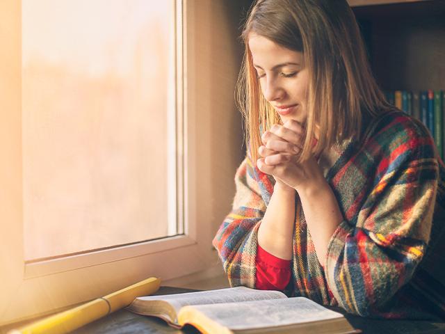 woman praying during covid19 pandemic with her Bible in front of her