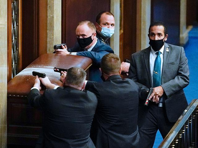 U.S. Capitol Police with guns drawn stand near a barricaded door as protesters try to break into the House Chamber at the U.S. Capitol on Wednesday, Jan. 6, 2021, in Washington. (AP Photo/Andrew Harnik)