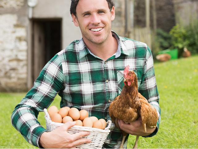 man holding a chicken and a basket of eggs from the hen