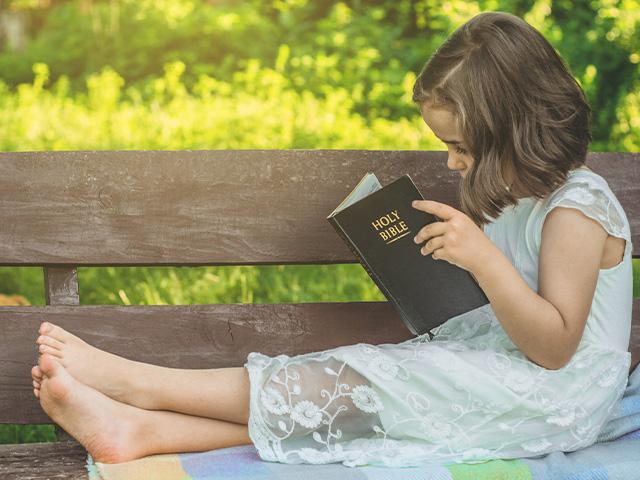 child-reading-bible-outdoors