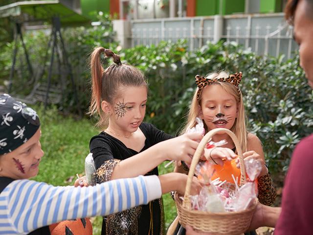 children on halloween getting trick or treat candy from person in a house