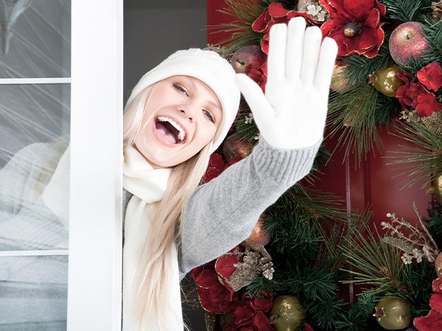 Woman waving from her front door wearing Christmas clothing