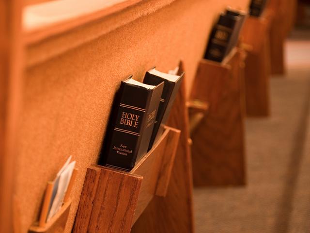 a church pew with Bibles in the book holders