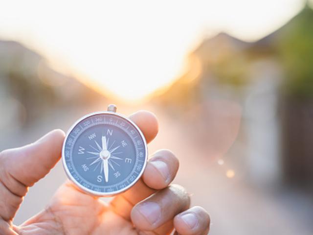 hand holding a compass in the sunshine