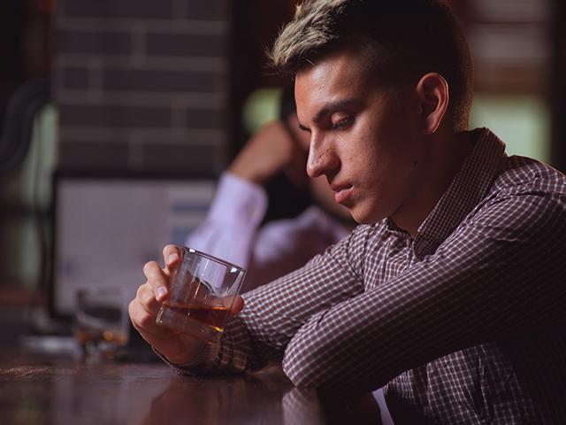 man sitting at bar staring into his glass