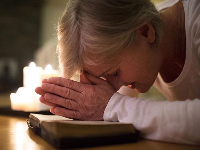 woman praying with head on her Bible and prostrate