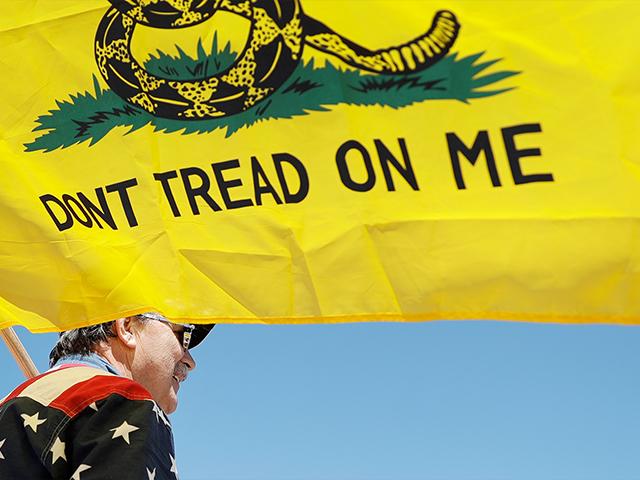 A man holds a flag as he attends a rally to protest stay-at-home orders put into place due to the COVID-19 outbreak Tuesday, April 21, 2020, outside the Missouri Capitol in Jefferson City, Mo. (AP Photo/Jeff Roberson)