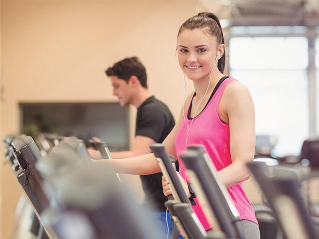 young woman working out at a gym and wearing earbuds