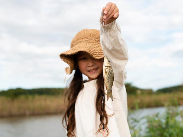 little girl holding up the fish she caught
