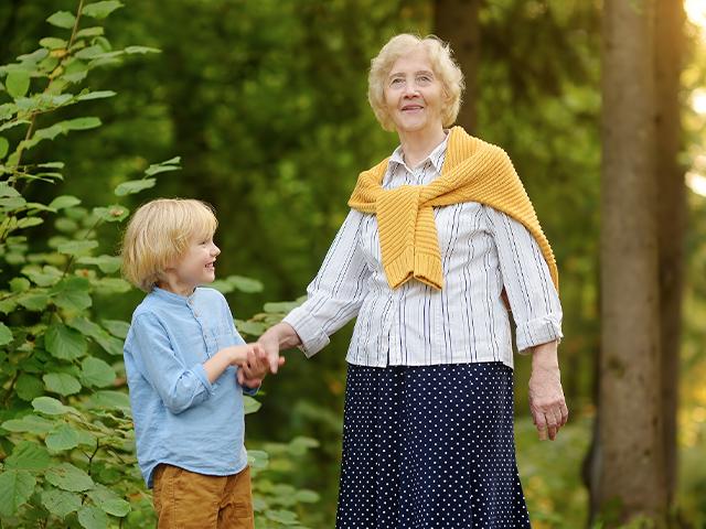 grandmother and grandson holding hands on a path outside