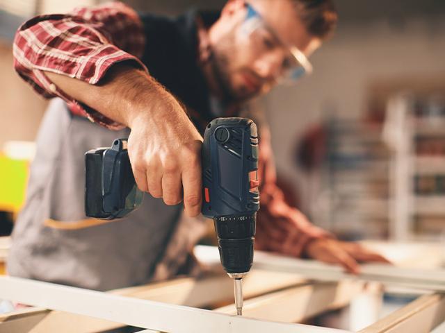 man drilling a piece of wood