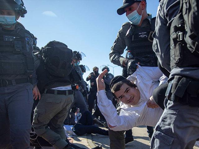 Israeli police officers clash with ultra-Orthodox Jews in Ashdod, Israel, Sunday, Jan. 24, 2021. (AP Photo/Oded Balilty)