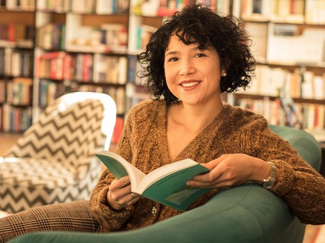 woman sitting on a couch in a library with a book