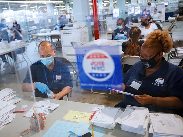 Workers wear personal protective equipment and are separated in pairs from fellow employees by plastic shields as they process ballots at a Board of Elections facility, Wednesday, July 22, 2020, in New York. (AP Photo/John Minchillo)