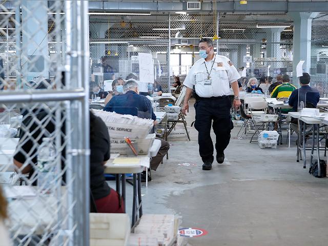 Security personnel walk through fenced workspaces at a Board of Elections facility, Wednesday, July 22, 2020, in New York. (AP Photo/John Minchillo)