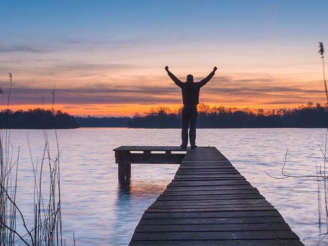 sunset, man on pier with raised arms, rejoice