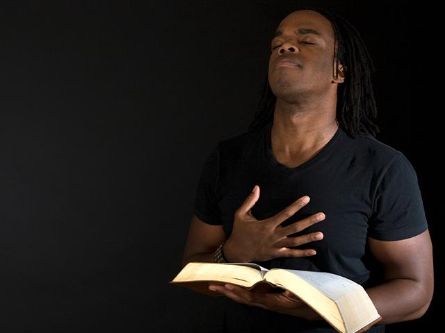 man reverencing God with his eyes closed and hand on his chest