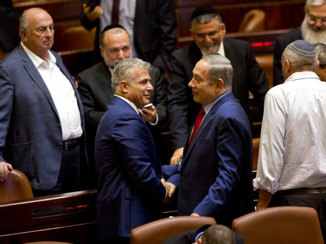 In this Monday, Oct. 31, 2016 photo, Israeli Prime Minister Benjamin Netanyahu, center right, shakes hands with Yair Lapid, leader of the Yesh Atid party, during a session at the Knesset.  (AP Photo/Sebastian Scheiner)