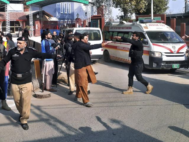 Police officers clear the way for ambulances leaving after carrying wounding people from bomb explosion site, at the main entry gate of police offices, in Peshawar, Pakistan, Monday, Jan. 30, 2023. (AP Photo/Muhammad Sajjad)
