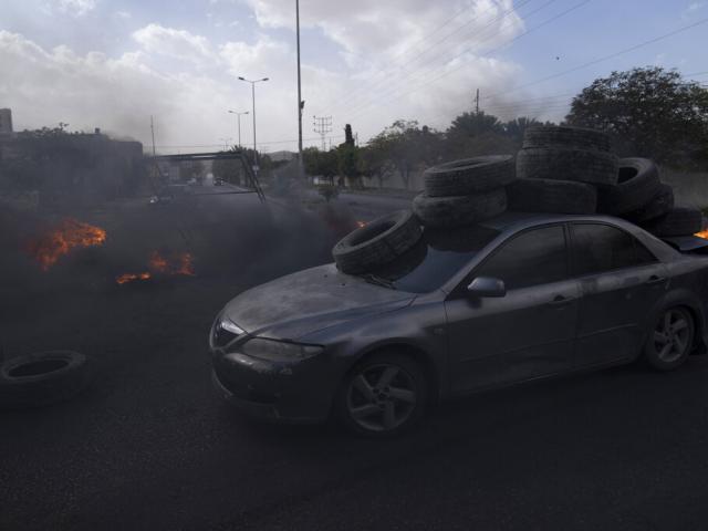Palestinian protesters block the main road with burning tires in the West Bank city of Jericho, Monday, Feb. 6, 2023. Israeli forces killed five Palestinian gunmen in a raid on a refugee camp. (AP Photo/Nasser Nasser)
