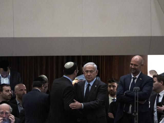 Israeli Prime Minister Benjamin Netanyahu embraces lawmaker Simcha Rothman on the floor of the Knesset, as people mass outside to protest his government&#039;s plan to overhaul the judicial system, Monday, March 27, 2023. (AP Photo/Maya Alleruzzo).