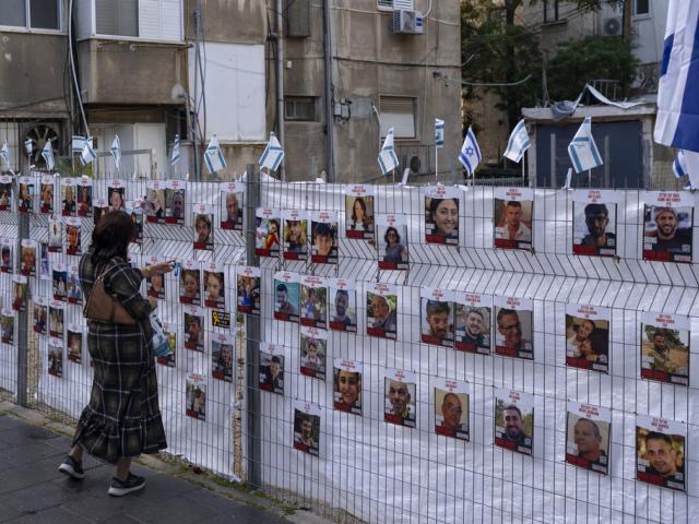 A woman looks at photographs of hostages, mostly Israeli civilians who were abducted during the Oct. 7, unprecedented Hamas attack on Israel, in Ramat Gan, Israel, Wednesday, Nov. 22, 2023. (AP Photo/Oded Balilty)