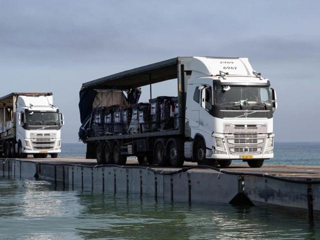 Trucks loaded with humanitarian aid from the United Arab Emirates and the United States Agency for International Development cross the Trident Pier before entering the beach in Gaza, May 17, 2024. (Staff Sgt. Malcolm Cohens-Ashley/U.S. Army Central via AP