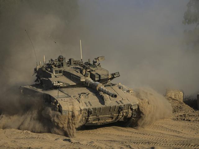 An Israeli soldier moves on the top of a tank near the Israeli-Gaza border, as seen from southern Israel, Sunday, July 14, 2024. (AP Photo/Tsafrir Abayov)
