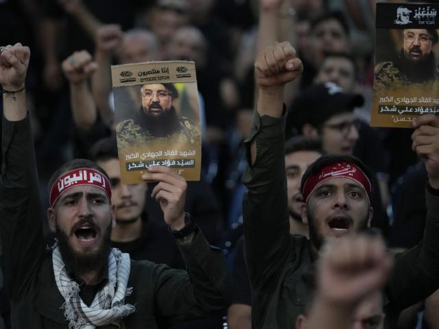 Hezbollah supporters shout slogans and hold up portraits that show the top commander Fouad Shukur, who was killed by an Israeli airstrike during his funeral procession in a Beirut, Lebanon suburb, Aug. 1, 2024. (AP Photo/Hussein Malla, file)