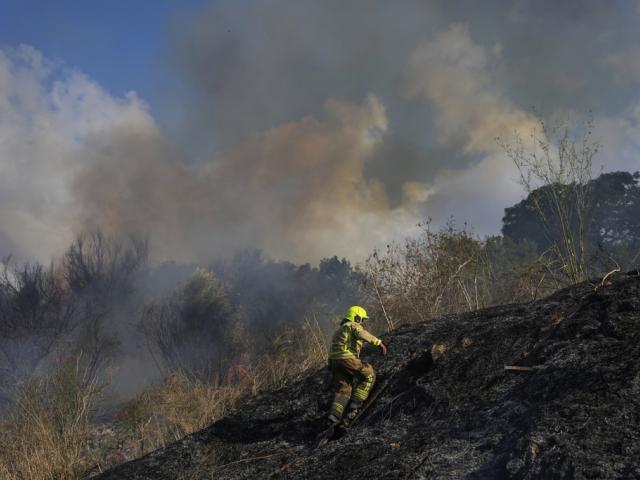 A firefighter works in the area around a fire after the military said it fired interceptors at a missile launched from Yemen that landed in central Israel on Sunday, Sept. 15, 2024. (AP Photo/Ohad Zwigenberg)