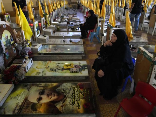 Women sit in a cemetery as they visit the graves of killed Hezbollah members in the southern suburbs of Beirut, Thursday, Sept. 19, 2024. (AP Photo/Hussein Malla)