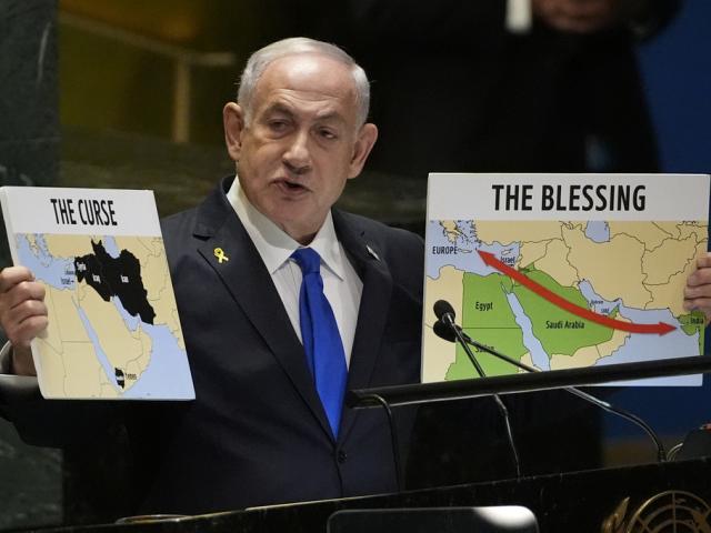 Prime Minister of Israel Benjamin Netanyahu hold signs as he addresses the 79th session of the United Nations General Assembly, Friday, Sept. 27, 2024. (AP Photo/Pamela Smith)