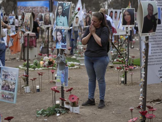 Victoria stands in front a picture of her sister, Yulia Waxer Daunt, as she visits the site of the Nova music festival, where hundreds of revelers were killed and abducted by Hamas, Monday, Oct. 7, 2024. (AP Photo/Ariel Schalit)