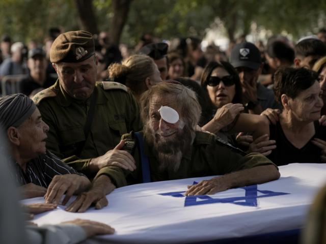 People mourn over the flagged-covered coffin of Israeli soldier Sgt. Amitai Alon, killed by a Hezbollah drone attack, during his funeral near Ramot Naftali, Israel, Monday, Oct. 14, 2024. (AP Photo/Leo Correa)