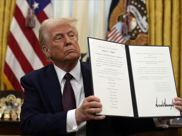 President Donald Trump holding up a order for clemency for anti-abortion protesters as he signs executive orders in the Oval Office of the White House, Thursday, Jan. 23, 2025, in Washington. (AP Photo/Ben Curtis)