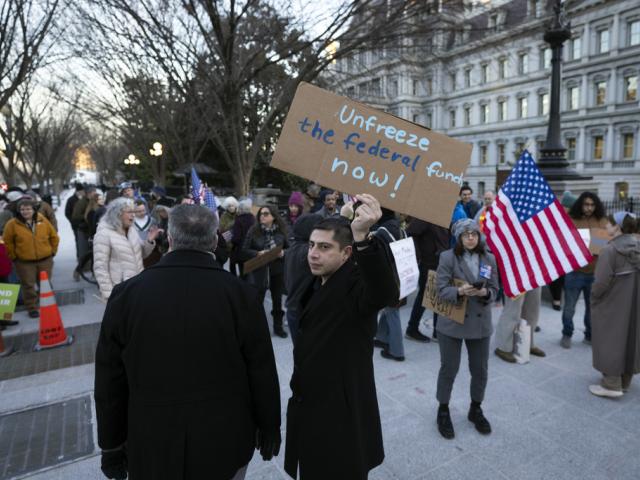 People protest against a funding freeze of federal grants and loans following a push from President Trump to pause federal funding near to the White House in Washington, Jan. 28, 2025. (AP Photo/Ben Curtis)