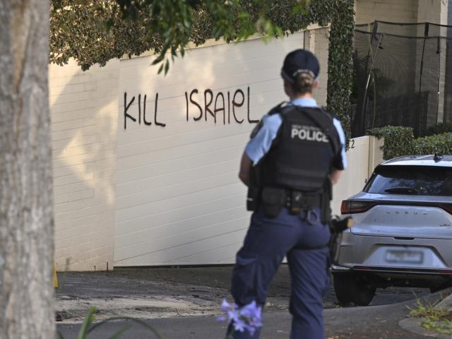  police officer stands near where anti-Israel graffiti is painted on a wall in Sydney, Australia, on Dec. 11, 2024. (Mick Tsikas/AAP Image via AP)