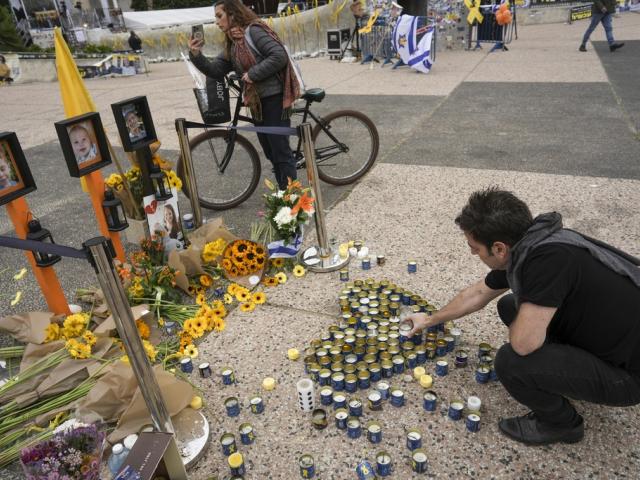 A man places a candle in a memorial for deceased hostages Shiri Bibas, her two children, Ariel and Kfir and Oded Lifshitz at &#039;Hostages Square&#039; in Tel Aviv, Israel, Saturday Feb. 22, 2025. (AP Photo/Oded Balilty)