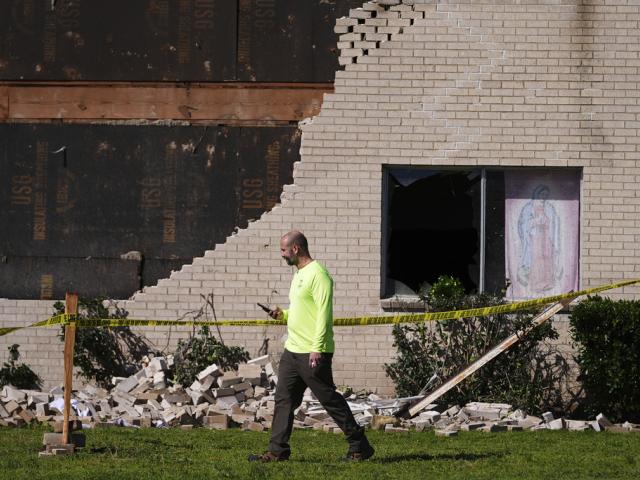 A person walks near a building damaged by an early morning storm that hit the Dallas region Tuesday, March 4, 2025, in Irving, Texas. (AP Photo/Julio Cortez)