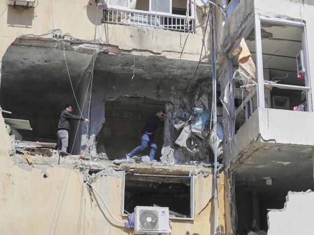 Residents check the site of Saturday&#039;s Israeli airstrike in the southern port city of Tyre, Lebanon, Sunday, March 23, 2025. (AP Photo/Mohammad Zaatari)