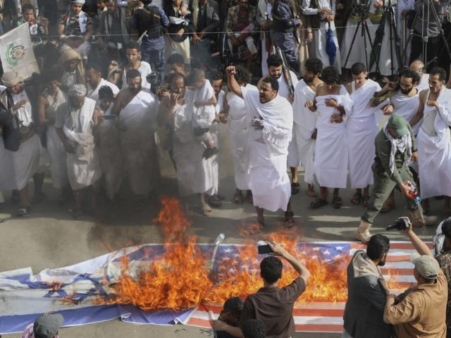 Houthi supporters in Muslim pilgrim dress burn American and Israeli flags during an anti-U.S. and anti-Israel rally in Sanaa, Yemen, May 30, 2025. (AP Photo/Osamah Abdulrahman)