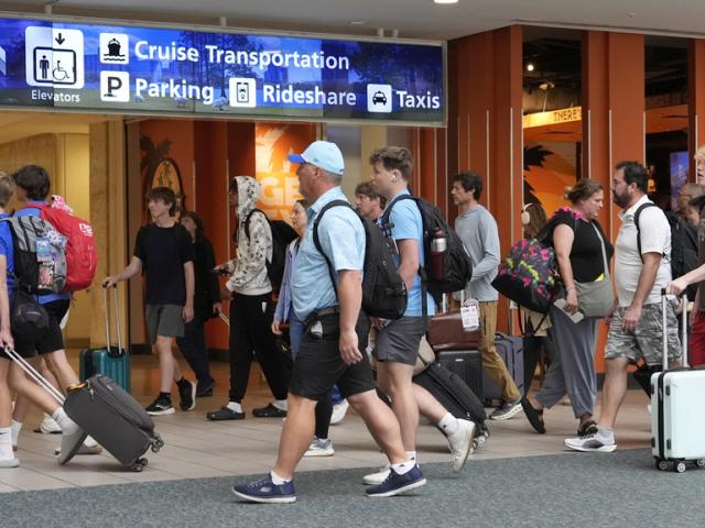 Holiday travelers make their way through the terminal at Orlando International Airport Thursday, July 3, 2025, in Orlando, Fla. (AP Photo/John Raoux)