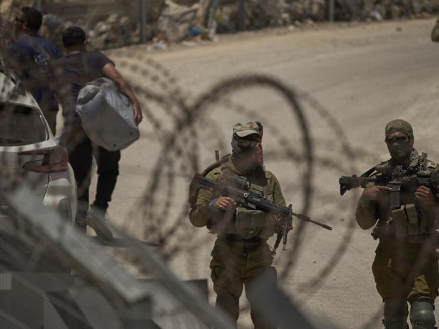 Israeli soldiers stand guard as Syrian Druze people cross back into Syria at the Israeli-Syrian border, in the Israeli-controlled Golan Heights town of Majdal Shams, Thursday, July 17, 2025. (AP Photo/Leo Correa)