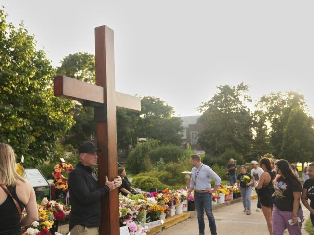 Dan beazley carries a cross at a memorial at Annunciation Catholic Church after Wednesday&#039;s school shooting, Thursday, Aug. 28, 2025, in Minneapolis. (AP Photo/Abbie Parr)