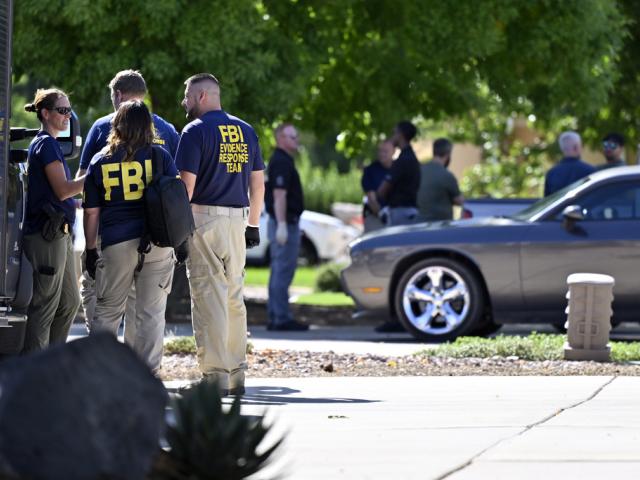 Federal law enforcement officials stand outside the family home of Tyler Robinson, the man accused of killing Turning Point USA CEO and co-founder Charlie Kirk, Sept. 12, 2025, in Washington, Utah. (AP Photo/David Becker)