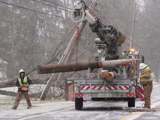 Utility crew workers replace a power pole snapped in two when high winds downed a tree in Sagamore Hills, Ohio, Monday, Dec. 29, 2025. (AP Photo/Sue Ogrocki)