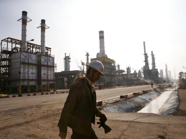 In this Dec. 22, 2014 file photo, an Iranian oil worker makes his way through Tehran&#039;s oil refinery south of the capital Tehran, Iran. (AP Photo/Vahid Salemi, File)