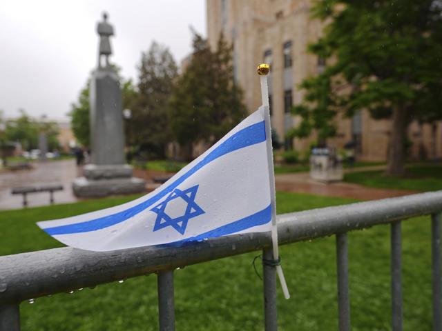 The flag of Israel tops a makeshift memorial for victims of an attack outside of the Boulder County, Colo., courthouse as a light rain falls Tuesday, June 3, 2025, in Boulder, Colo. (AP Photo/David Zalubowski)