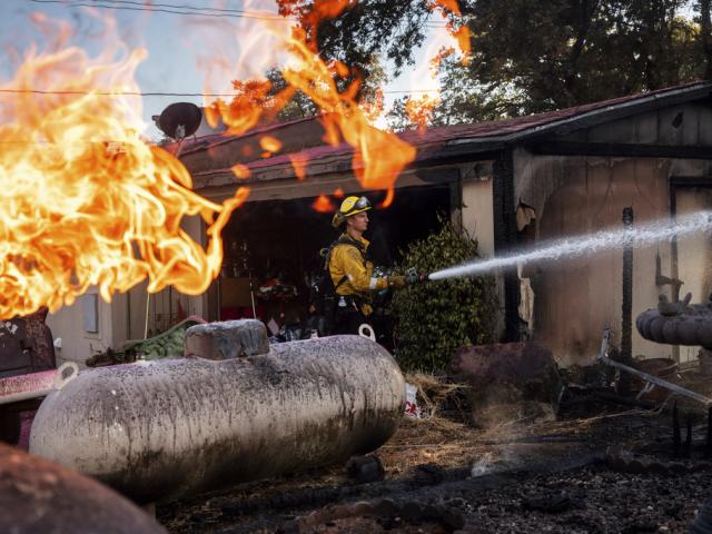 Firefighter Nolan Graham sprays water around a scorched garage as the Boyles fire burns in Clearlake, Calif., on Sunday, Sept. 8, 2024. (AP Photo/Noah Berger)