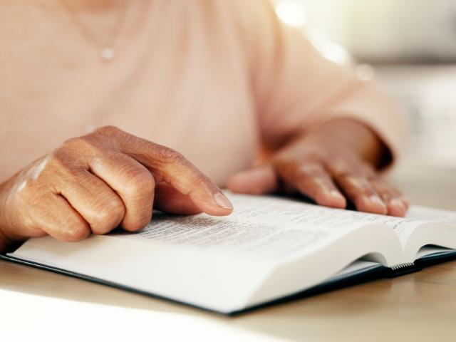 Person pointing to their Bible
